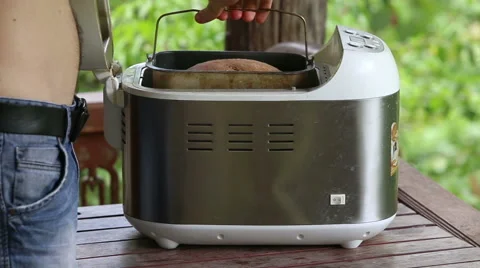 Man takes container out of breadmaker and puts on table Stock Footage 48946692