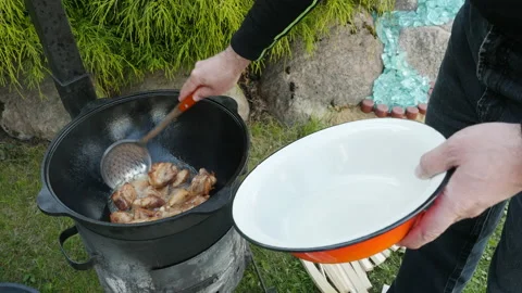 A man takes cooked meat from cauldron. Cooking process, frying pork meat 스톡 동영상 131542104