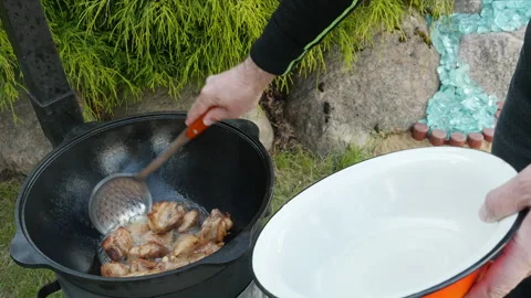 A man takes cooked meat from cauldron. Cooking process, frying pork meat Stock-Footage 131544355