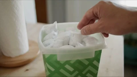 Man takes dish detergent pod package out of bin to put into washing machine Stock Footage 161801195