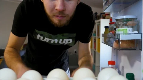 The man takes eggs from the fridge. View from inside the fridge. 4K Stock Footage 128597029