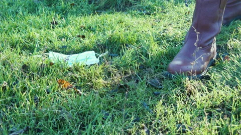 Man takes off face mask, throws it on ground and crushes it with foot in park Stock-Footage 149311202