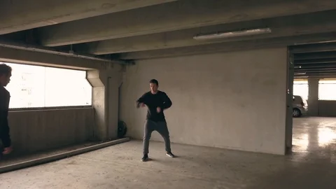 Man takes fighting stance with back to a plain wall and is attacked by a Stock Footage 99254294