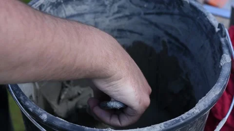 Man takes glue from a bucket and puts with spatula on decorative facing brick Video stock 136432003