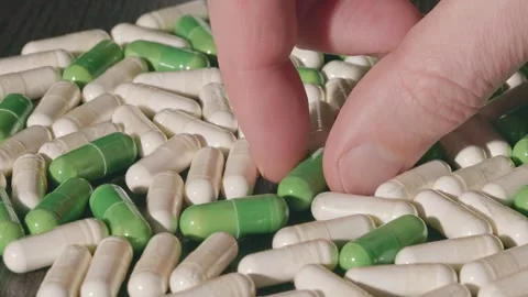 A man takes a green capsule from a multitude of capsules Stock Footage 270412657