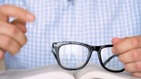 Man takes his glasses and reads a book close up Stock Footage