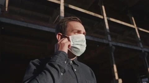 The man takes off his mask. Construction of an abandoned building at sunset Stock Footage 140954833