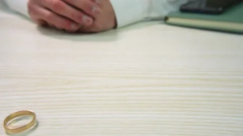Man takes off his wedding ring and throws it on the table Видео 299636114