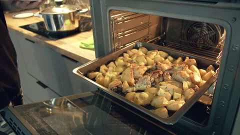 Man takes a home-cooked dinner out of the oven on a tray and puts food on his Stock Footage 166127141