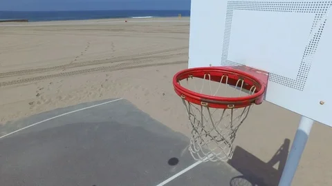 A man takes a jump shot while playing one-on-one basketball hoops on a beach cou Stock Footage