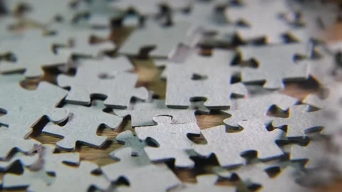 A man takes a magnifying glass from a table on which a puzzle lies. Stock Footage 304267334