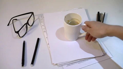 The man takes a mug of coffee from the table and leaves a coffee imprint on the Video stock 83467387