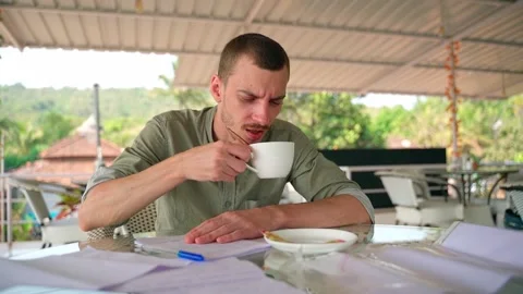 Man takes notes in a notebook, takes a sip of coffee and looks into the distance Video stock 231336793