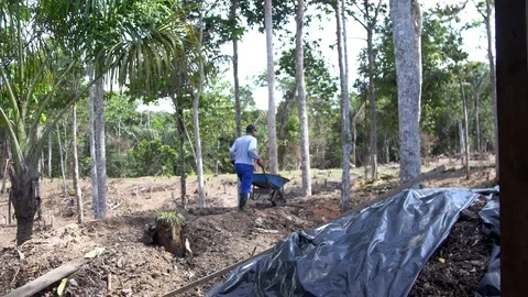 A man takes out a bunch of garbage on a wheelbarrow. asian dump Video stock 127369686