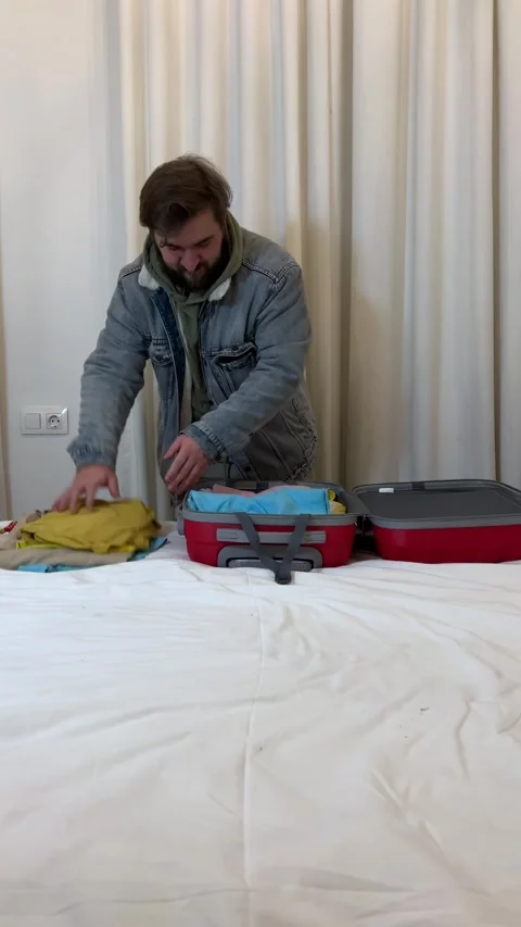 Man takes out clothes from red suitcase Stock Footage 304767817