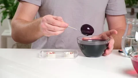 A man takes out colored Easter eggs from colored water. Stock Footage 236659958