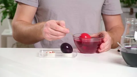 A man takes out colored Easter eggs from colored water. Stock Footage 236659967