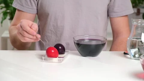 A man takes out colored Easter eggs from colored water. Stock Footage 236660169