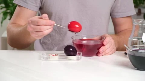 A man takes out colored Easter eggs from colored water. Stock Footage 236920564