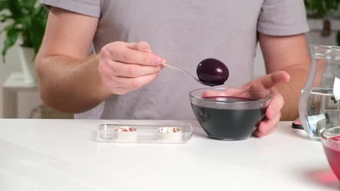 A man takes out colored Easter eggs from colored water. Stock Footage 236920768