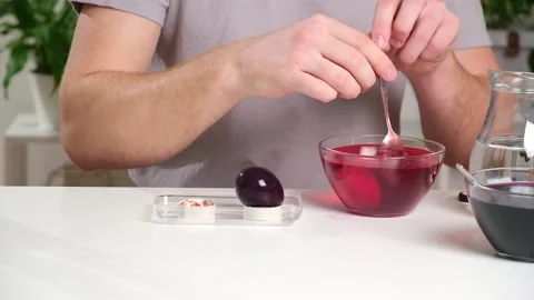 A man takes out colored Easter eggs from colored water. Stock Footage 237858650