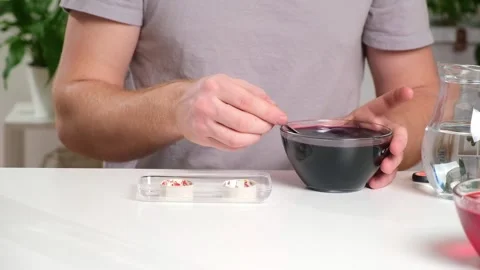 A man takes out colored Easter eggs from colored water. Stock Footage 244803484