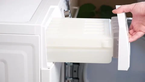 A man takes out a container from dryer to collect water squeezed out of wet Stock Footage 187812191
