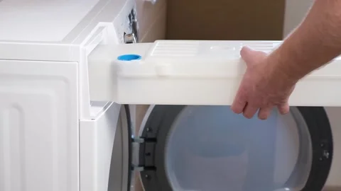 A man takes out a container from dryer to collect water squeezed out of wet Stock Footage 190638650