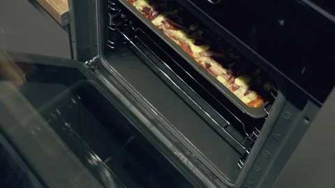A man takes out a hot baking sheet with homemade pizza from the oven, close-up Stock Footage 165711319