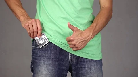Man takes out new condom from jeans pocket and makes gesture thumb up Stock Footage