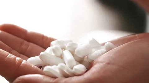 Man takes pills vitamins or drugs tablets in hand variety of white pills on palm Stock Footage 336586261