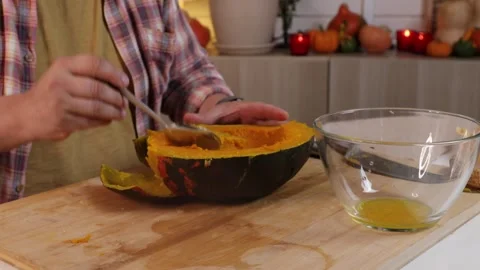 A man takes the pulp out of a pumpkin and puts it in a glass bowl to make pumpki Video stock 286103899