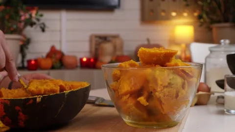 A man takes the pulp out of a pumpkin and puts it in a glass bowl to make pumpki Stock Footage 286103987