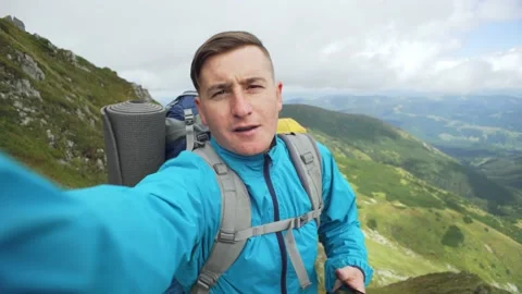 Man takes a selfie with a camera during a vacation in the mountains while hiking Stock Footage 232992959