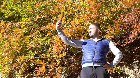 A man takes a selfie in the mountains on a mobile phone. Stockbeeldmateriaal 101392502