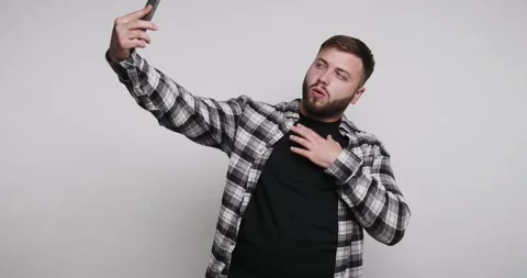 Man takes selfie in plain setting while wearing a checkered shirt and makin.. Stock-Footage 326798521