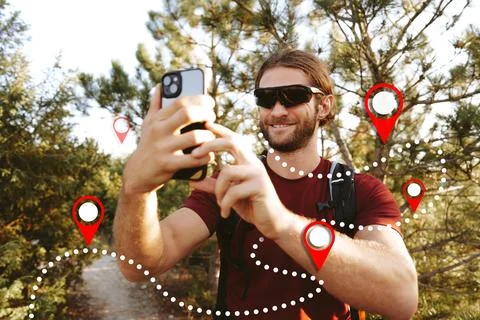 Man takes a selfie while looking at a map app for navigation in the woods Stock Photos