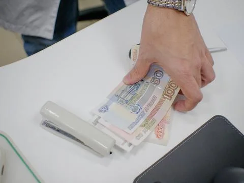A man takes a stack of Russian paper money rubles from the table with his hand 스톡 사진