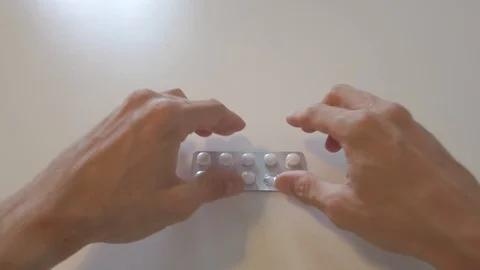 Man Takes a Tablet From the Blister Pack and Puts on White Table Stock-Footage 130068287