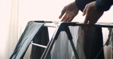 The man takes off things from drying rack clothes. Stock Footage 88048839