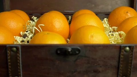 The man takes the two oranges that lie in the chest. Stockbeeldmateriaal 231111375