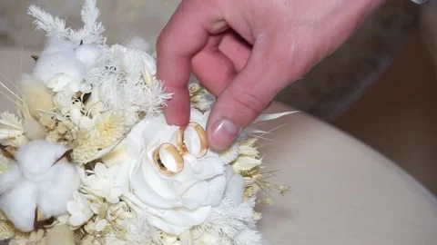 The man takes two wedding rings lying on the bride's bouquet Stock Footage 238020236