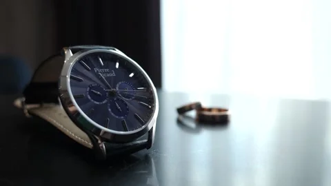 The man takes the watch from the table and puts it on his hand. Stylish holiday  Stock Footage 165682932