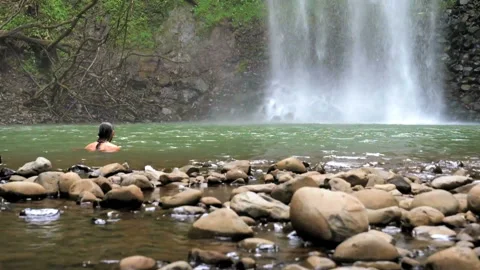 Man taking a bath next to a waterfall slow motion Stock Footage 96060673