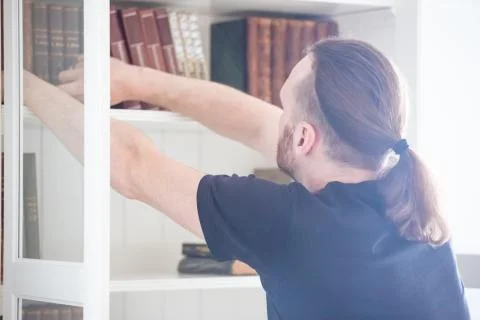 Man taking book from shelf 库存照片