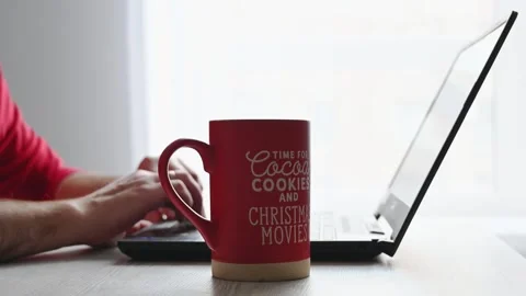 Man taking a break to enjoy hot chocolate from a festive red Christmas mug Stock Footage 290043593