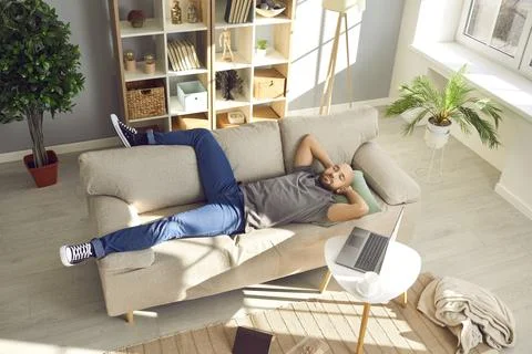 Man taking break from work on laptop and napping on comfortable couch in living Foto stock