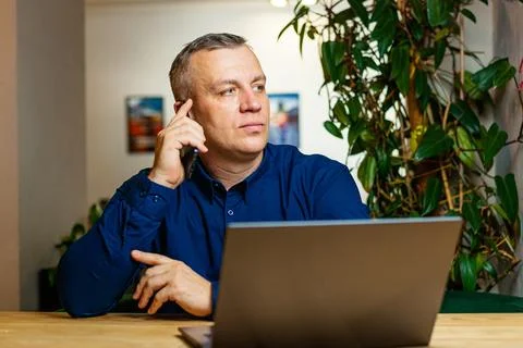 Man Taking Business Call While Working on Laptop Stock Photos