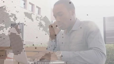 Man taking call, typing on laptop, rotating dotted globe, code overlays aiding Stock Footage 332285003