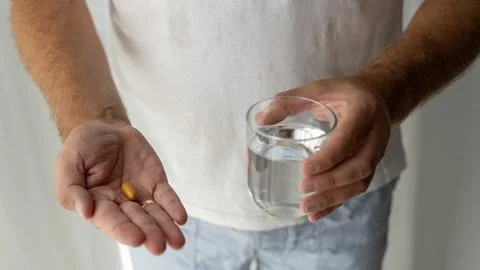 Man Taking a Capsule With a Glass of Water at Home Stock Photos